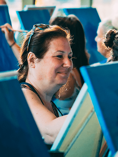 Artist smiling while canvas painting in Paint Nite self-care art class